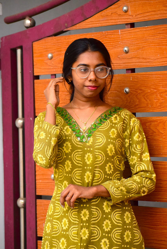 Woman wearing a green patterned dress with a wooden background