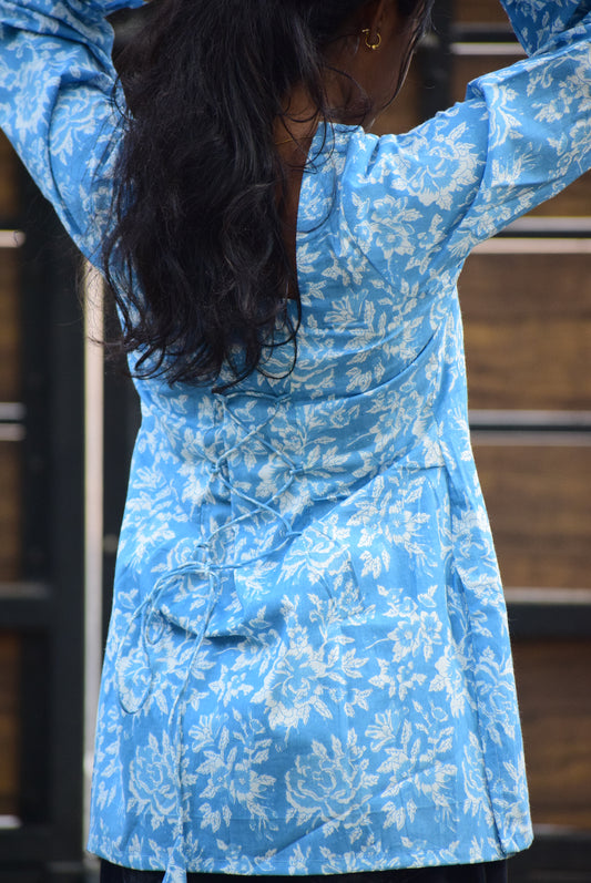 Person wearing a blue floral dress with a blurred background