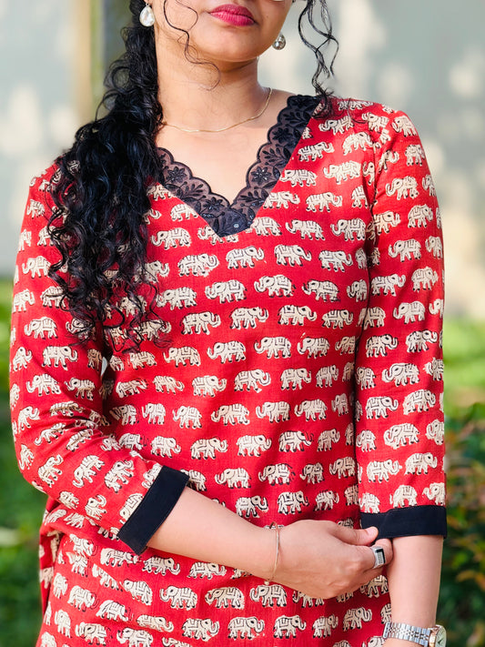 Woman wearing a red dress with elephant pattern and black lace details.
