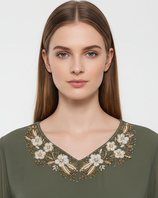 Green dress with floral embroidery on a mannequin against a neutral background