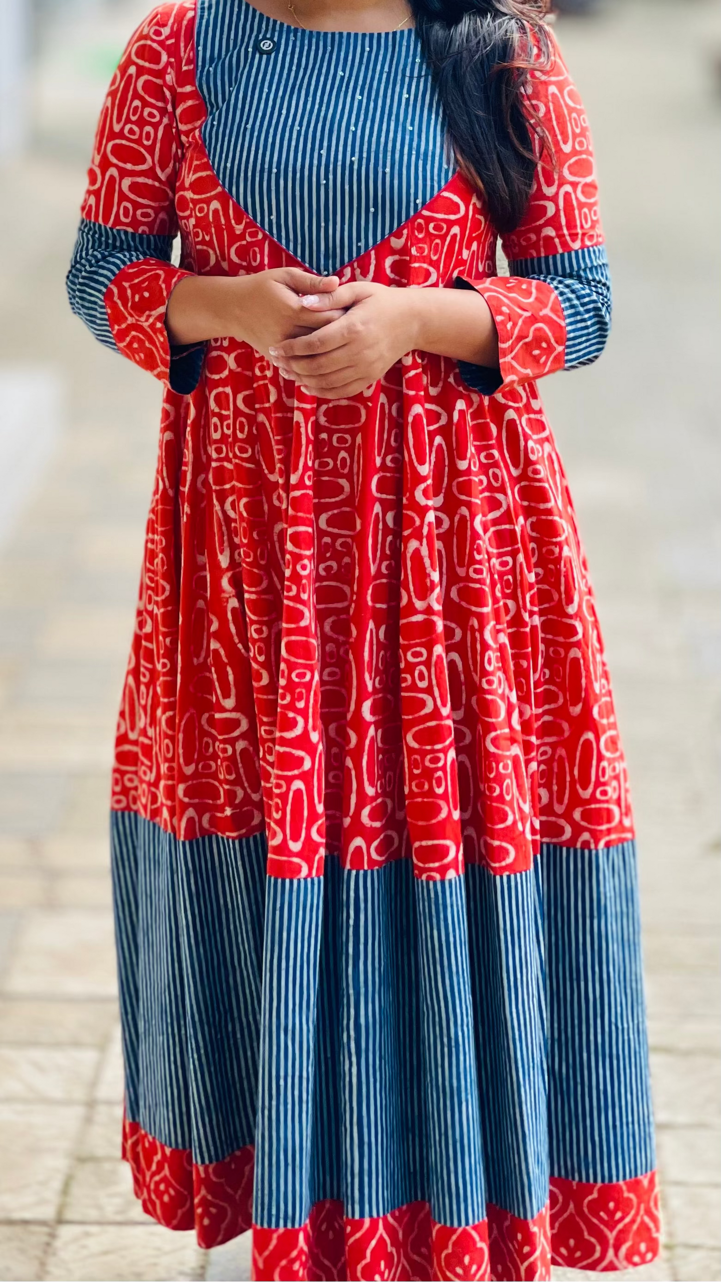 Woman wearing a red and blue patterned dress on a blurred background
