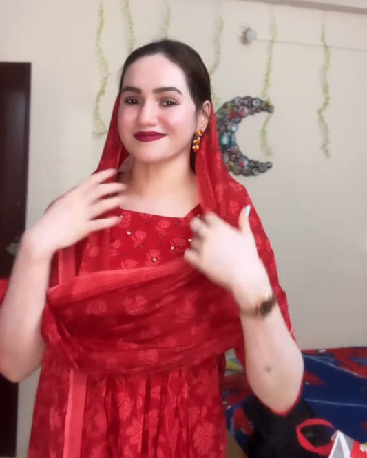 Woman in a red traditional outfit posing indoors.
