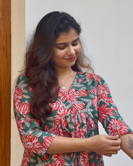 Woman wearing a floral dress standing against a plain background