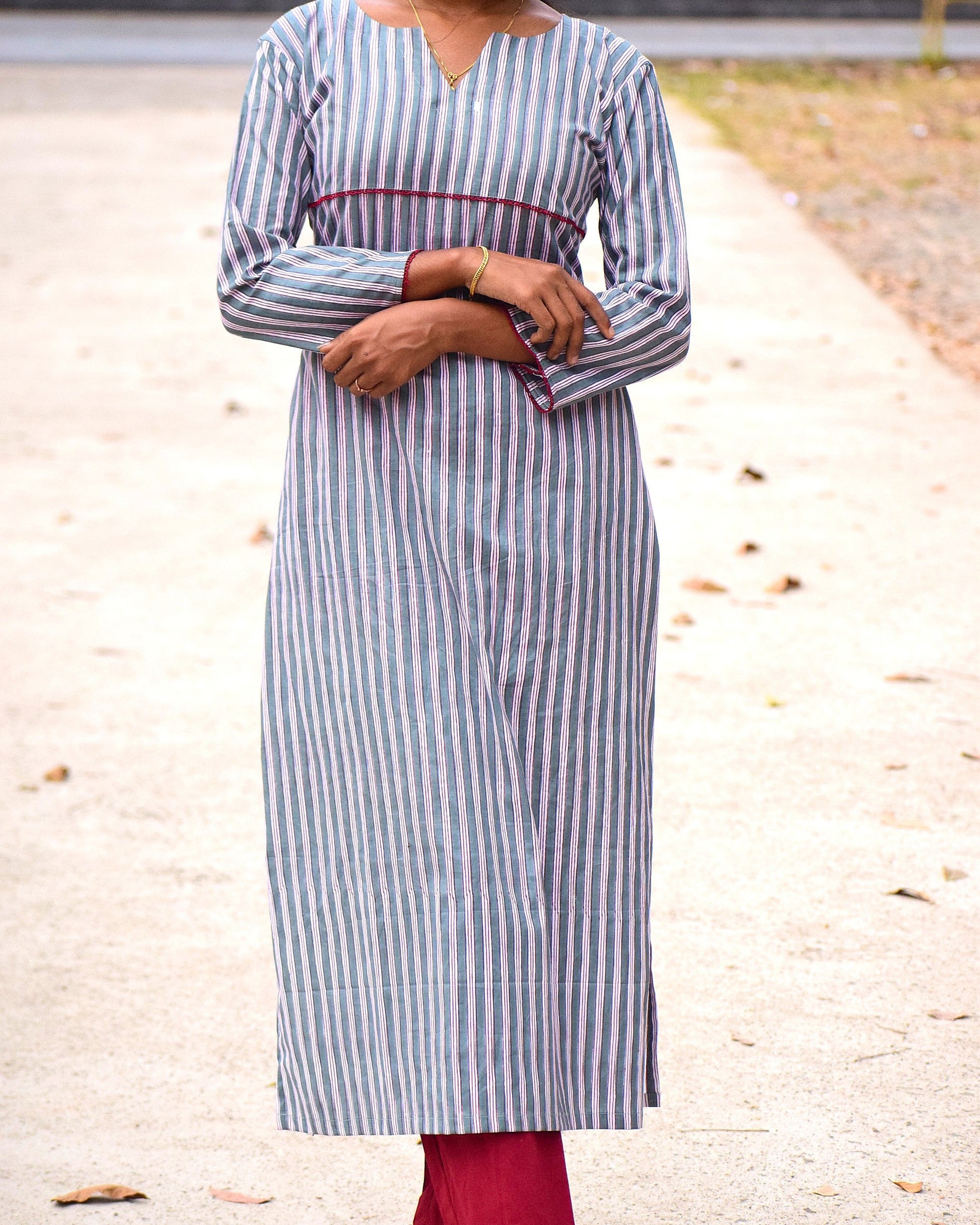 Person wearing a blue and white striped dress with red accents on a road.