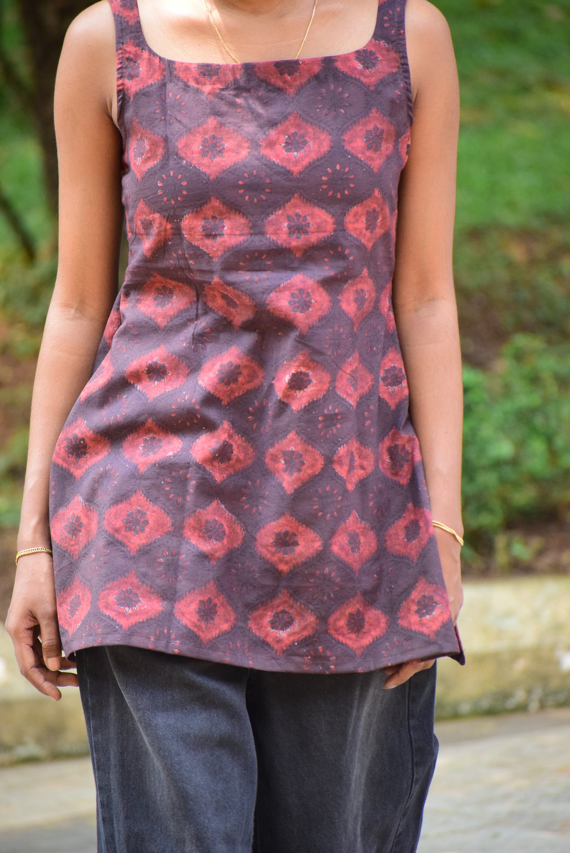 Person holding a patterned fabric with red geometric designs on a dark background.