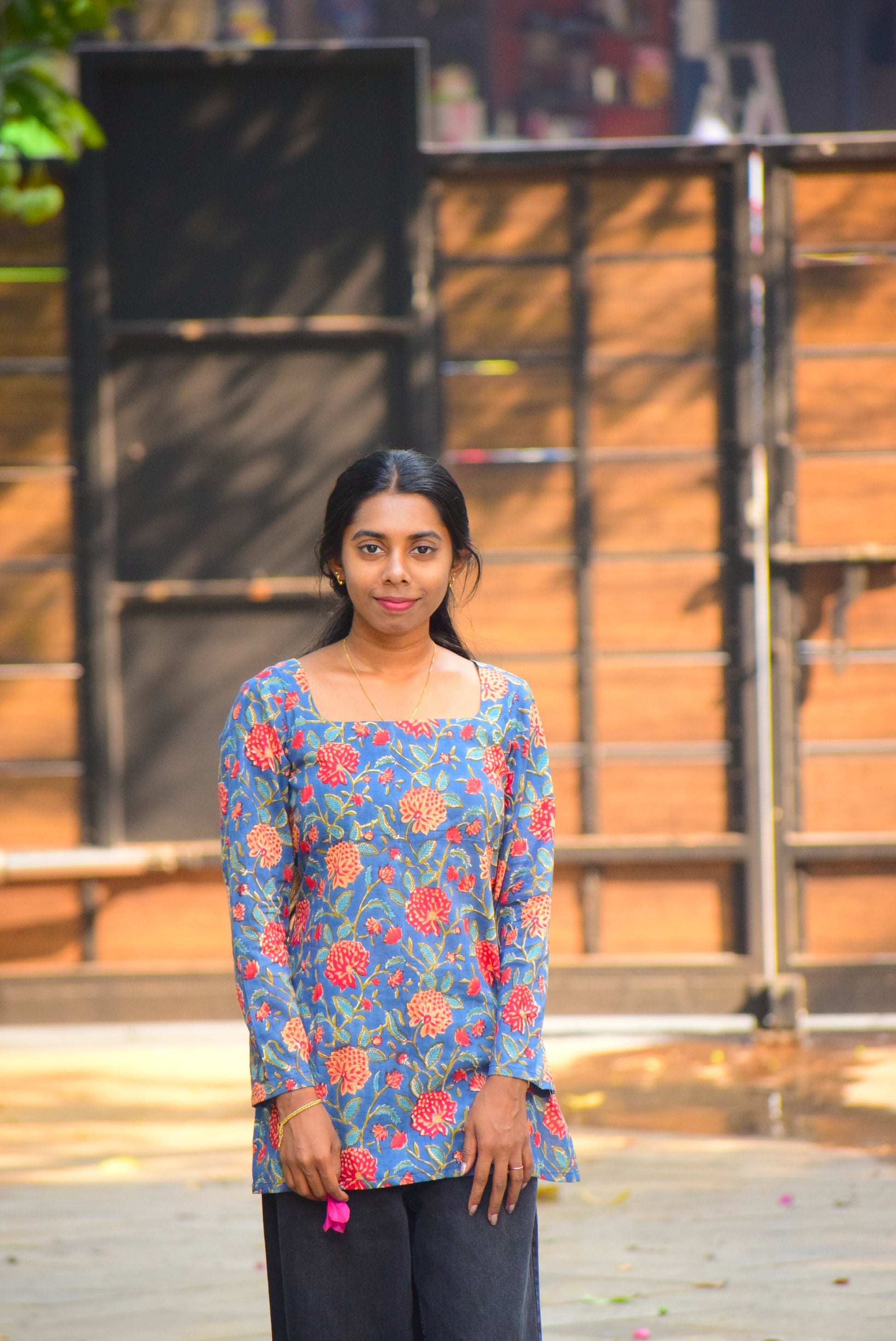 Woman wearing a blue floral top standing outdoors with a blurred background