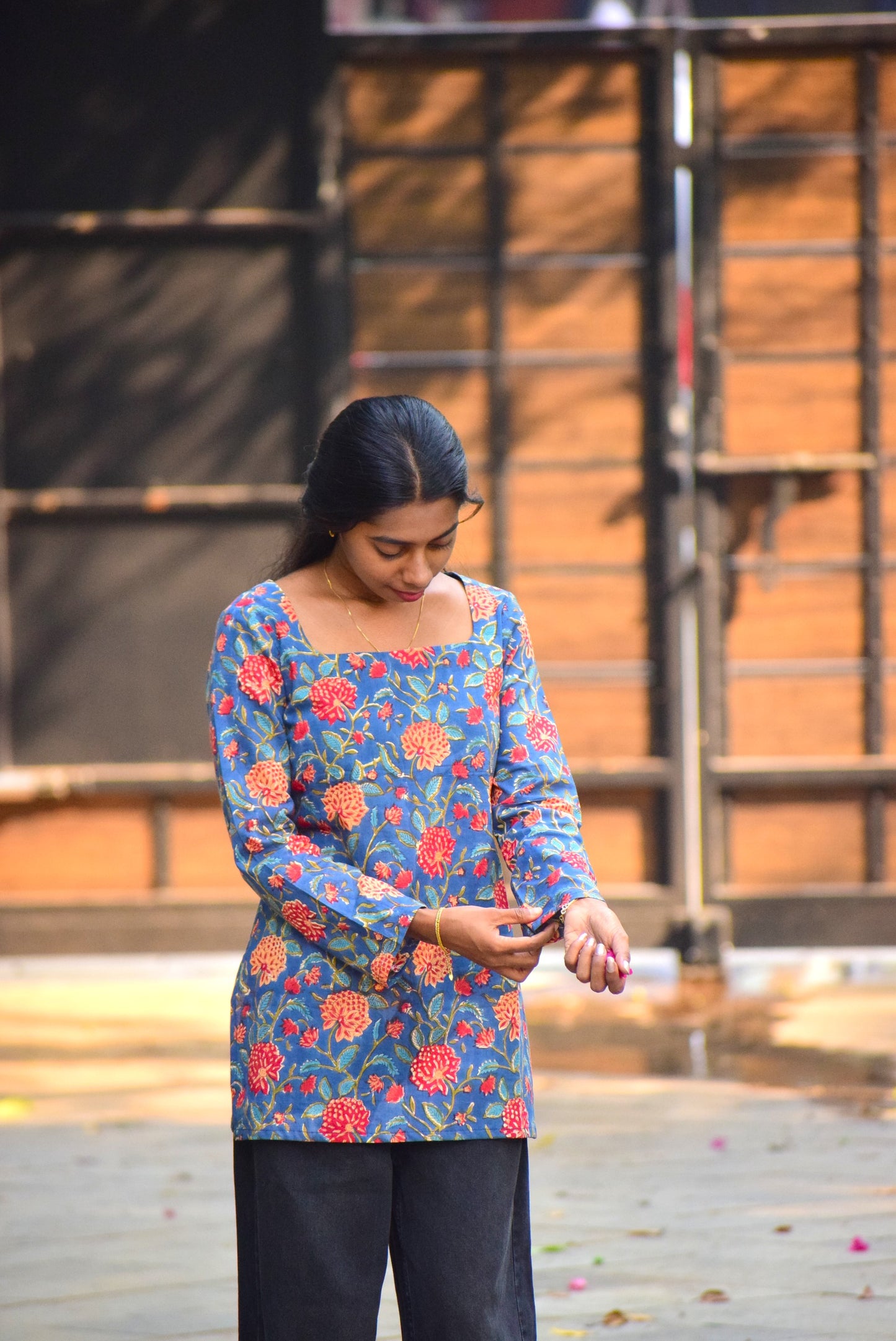 Woman wearing a colorful floral top standing outdoors with a blurred background