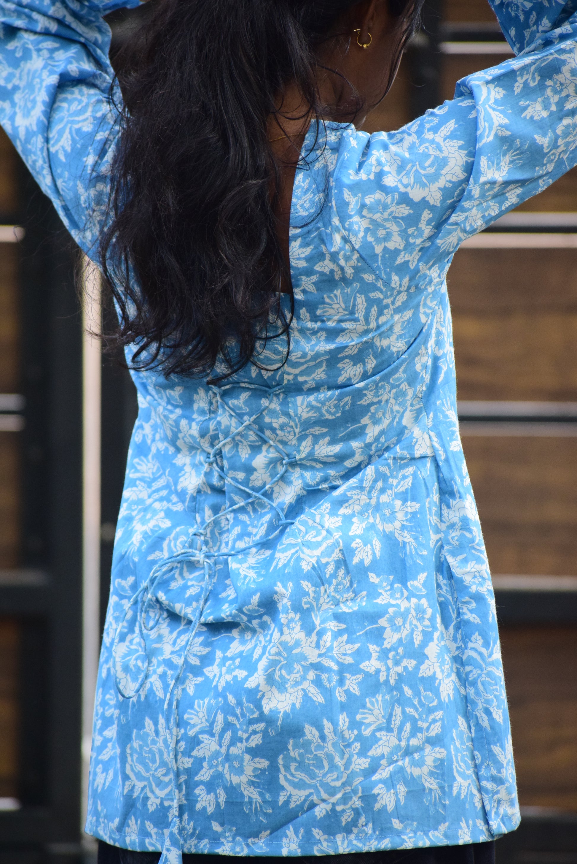 Person wearing a blue floral dress with a blurred background