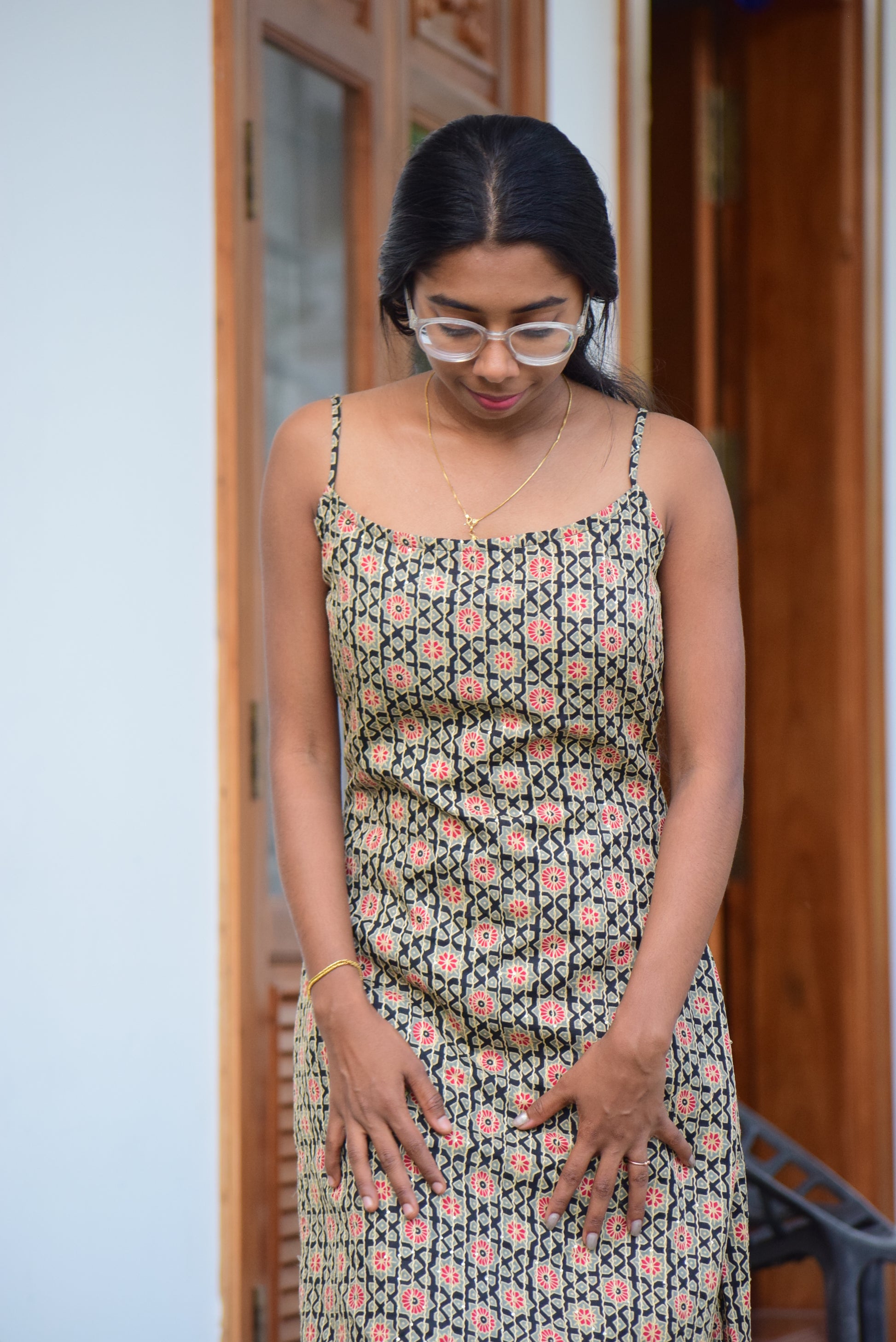 Woman wearing a patterned dress standing indoors with a neutral background