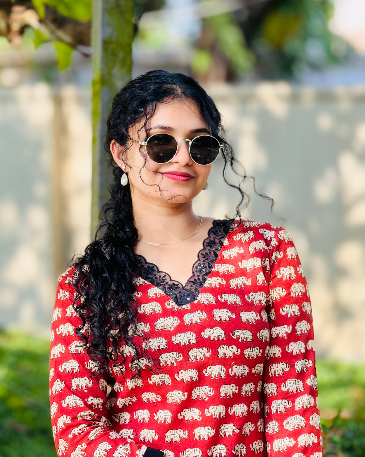 Woman wearing a red shirt with elephant pattern outdoors