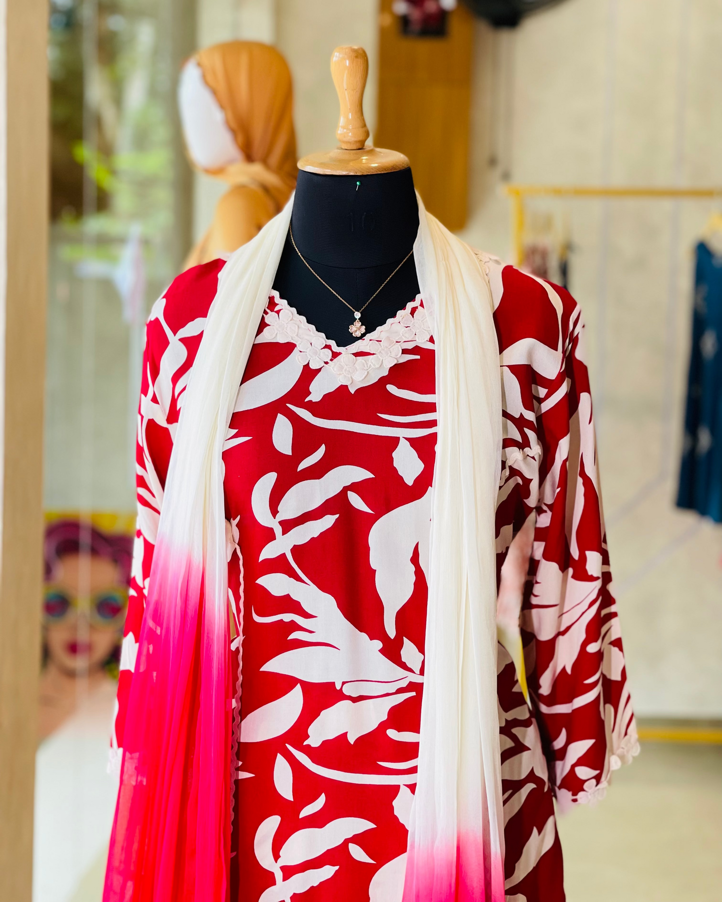 Red and white patterned dress with a matching shawl on a mannequin in a store setting.