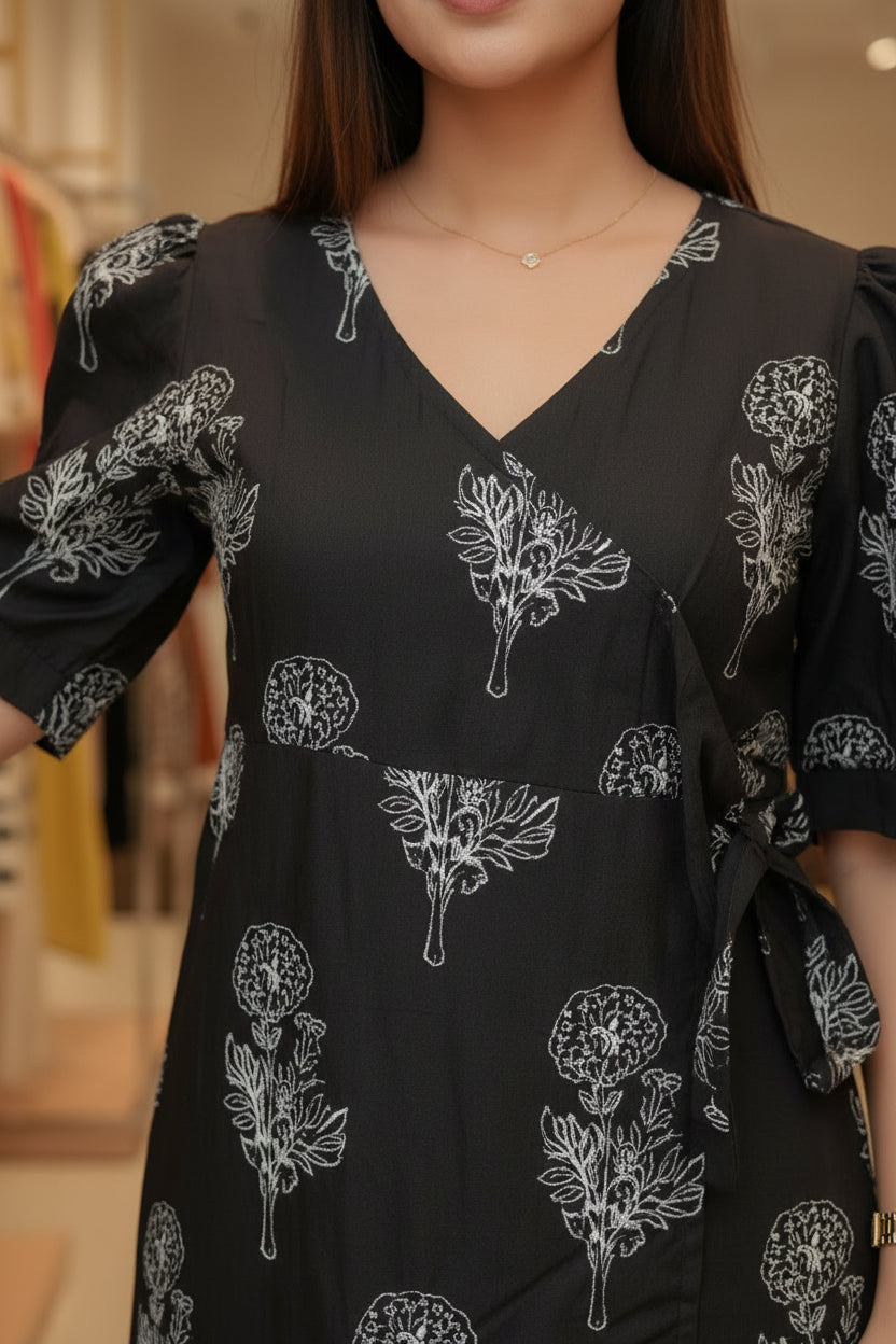 Black dress with white floral patterns on a mannequin in a store setting.