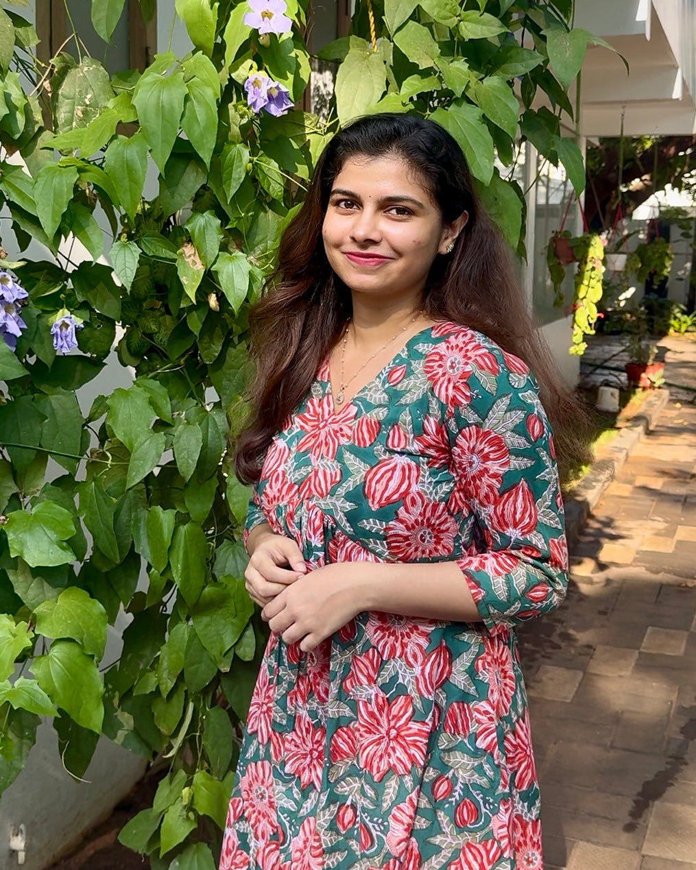 Woman in a floral dress standing in front of greenery