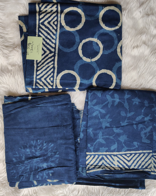 Three folded blue patterned cloths on a white textured surface