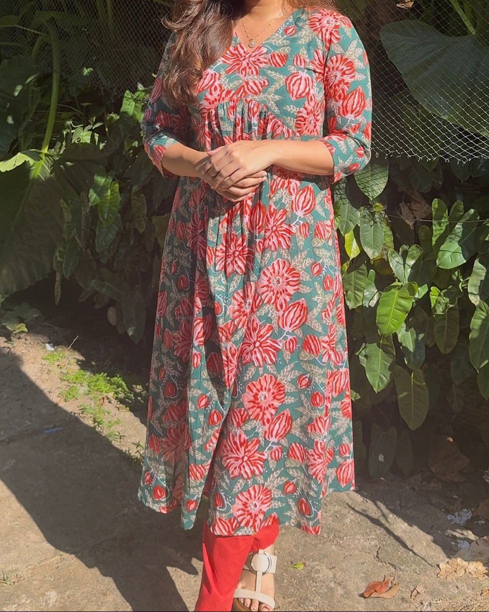 Woman wearing a floral dress standing in front of green foliage